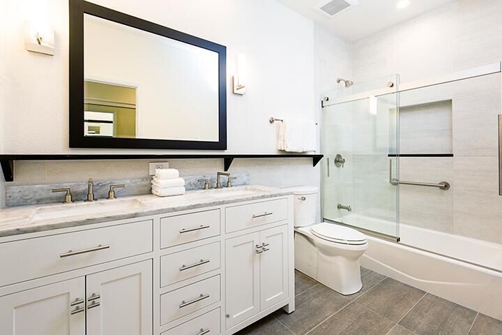 Black-framed vanity mirror next to sliding glass tub doors